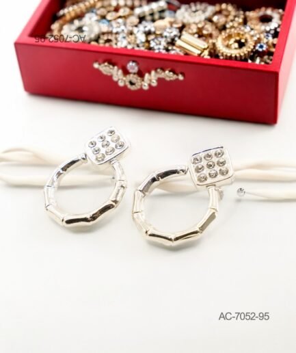 Aros o pendientes de diseño colgante en color plateado o metalizado, formados por una pieza superior cuadrada con incrustaciones de pequeños cristales y una argolla inferior con textura de bambú AC7052