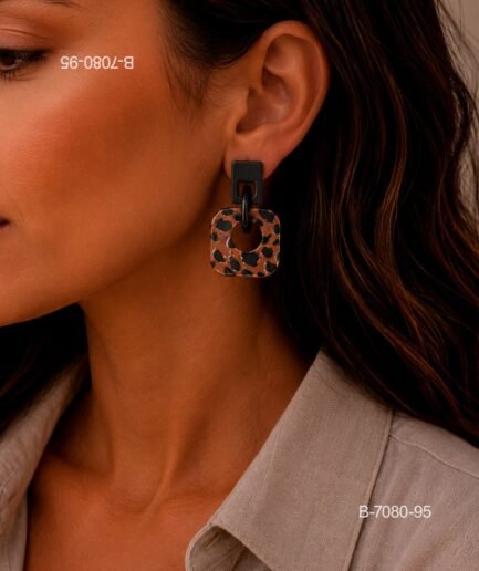 Aros o pendientes colgantes de diseño moderno, compuestos por un pequeño aplique superior rectangular de color negro y una pieza colgante cuadrada con estampado animal print B7080